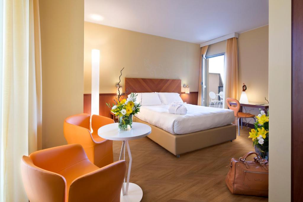 a hotel room with a bed and a table and chairs at UNA Hotels Mediterraneo Milano in Milan