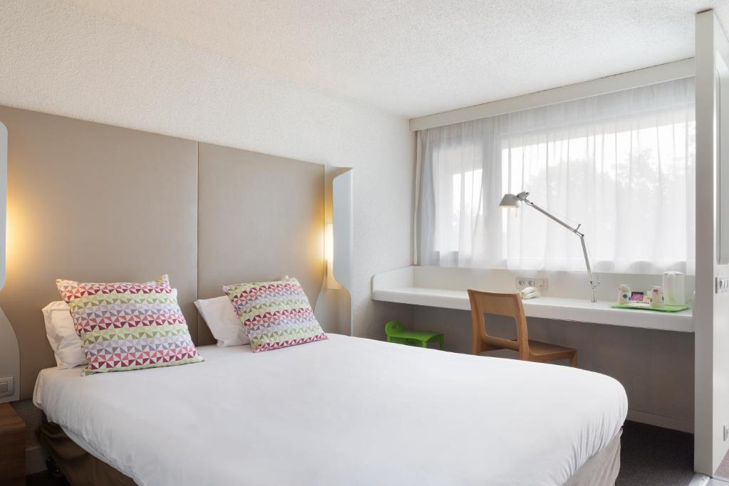 a bedroom with a large white bed and a window at Campanile Créteil - Bonneuil Sur Marne in Bonneuil-sur-Marne