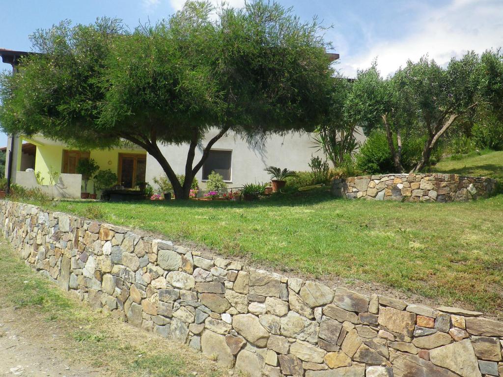 un muro di pietra di fronte a una casa con un albero di Centro di Turismo Equestre SHANGRILA' a Fluminimaggiore