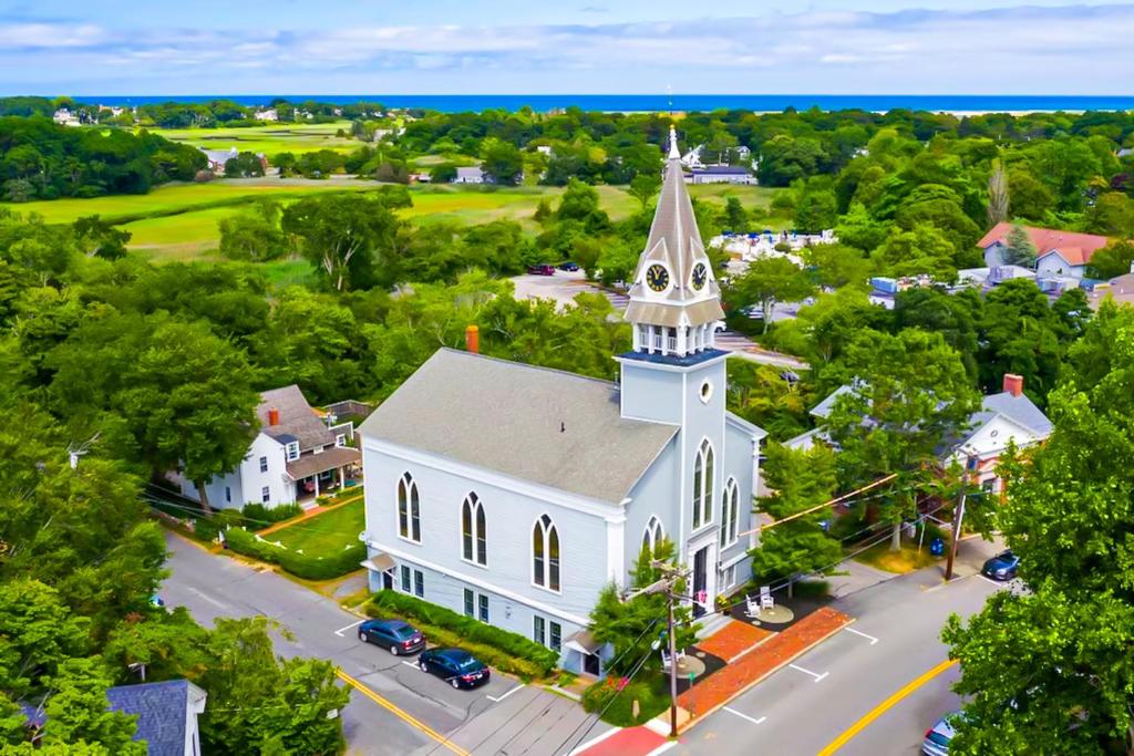 an aerial view of a white church with a steeple at The Belfry Meetinghouse in Sandwich