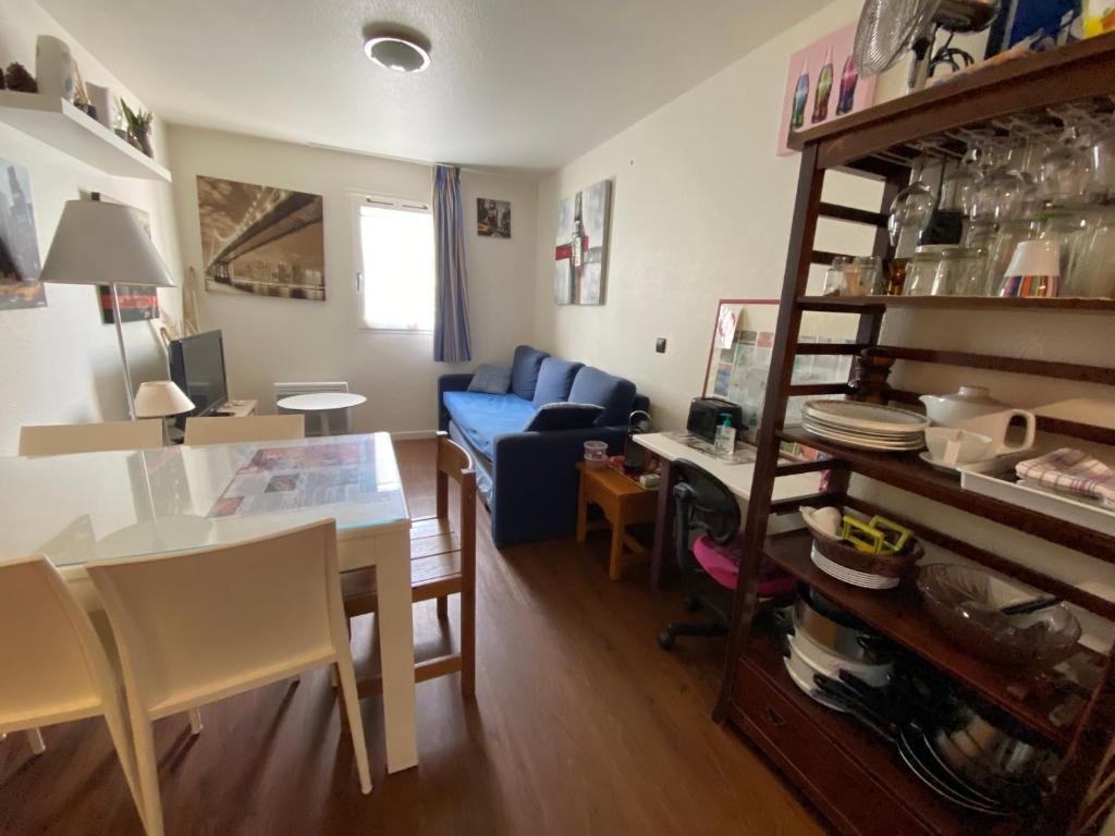 un salon avec une table et un canapé bleu dans l'établissement Studio sans chambre Soustons plage proximité golf océan, à Soustons