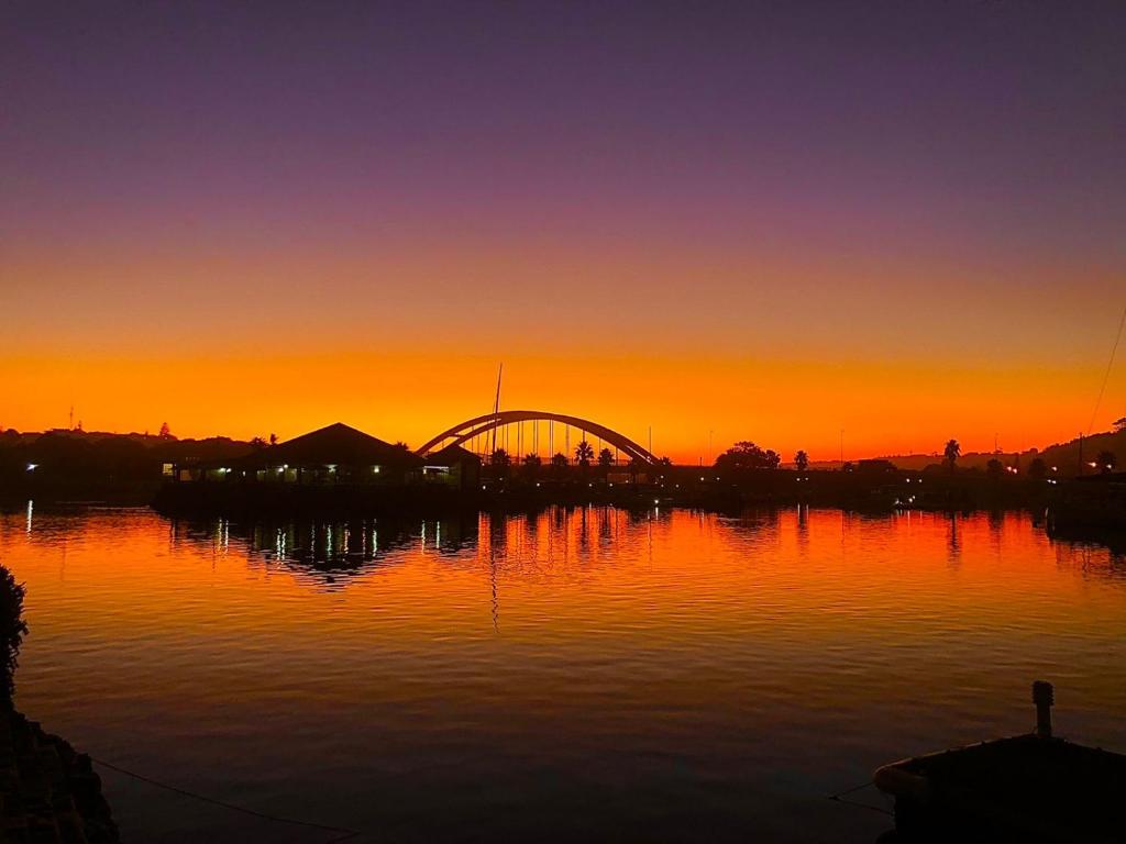 una puesta de sol sobre un cuerpo de agua con un puente en Royal Alfred Marina en Port Alfred