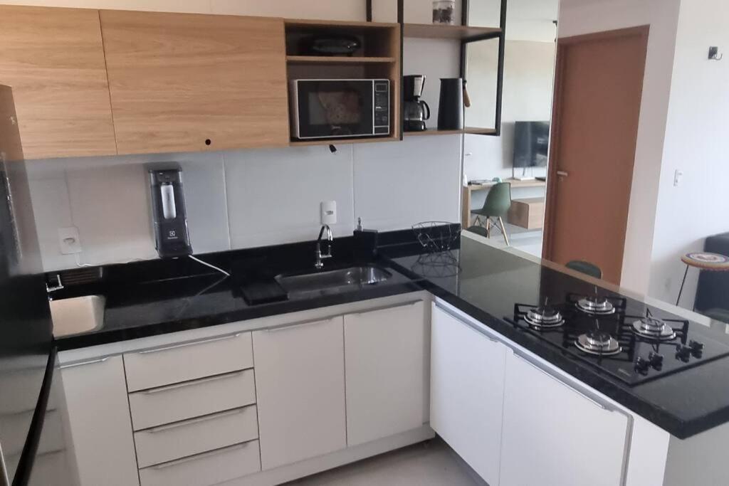 uma cozinha com armários brancos e um balcão preto em Cobertura Vista Mar Carapibus - Cariri Praia - Apartamento completo com 02 quartos em Conde