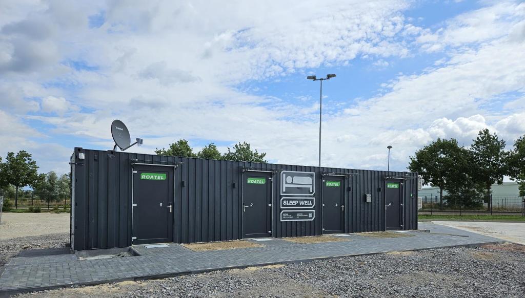 a black building with four doors and a parking lot at Roatel Oranienbaum-Wörlitz (A9) my-roatel-com in Oranienbaum-Wörlitz