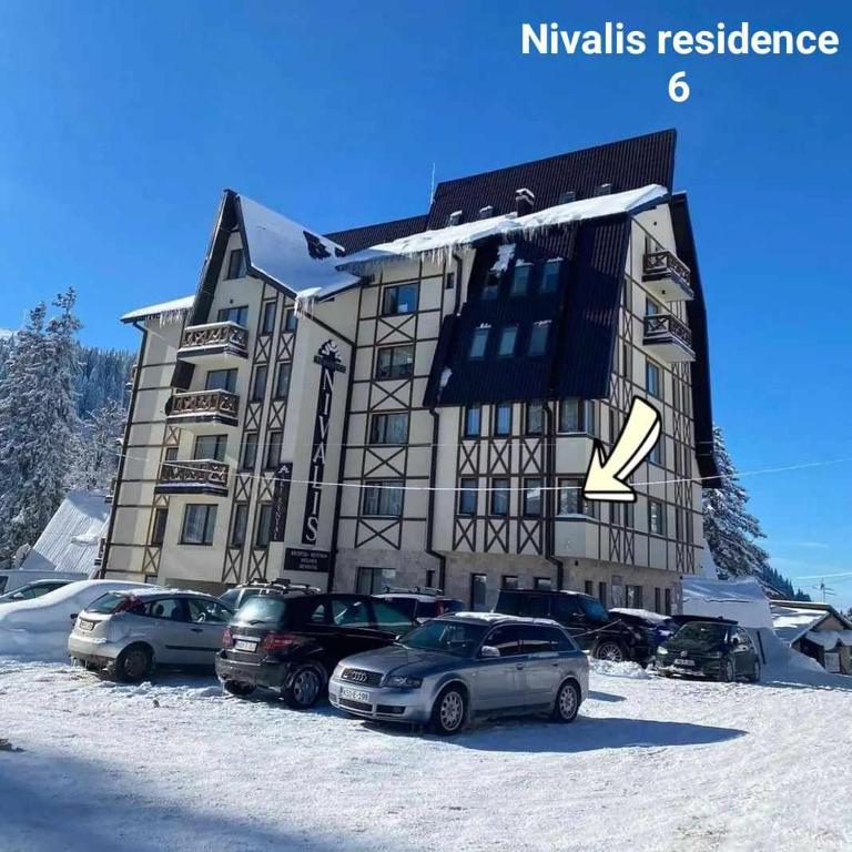a building with cars parked in front of it in the snow at Nivalis Residence 6 in Jahorina