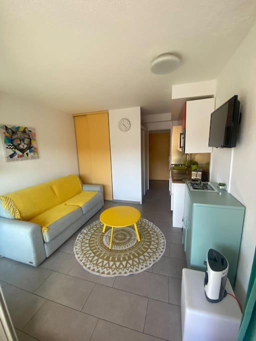 - un salon avec un canapé et une table jaune dans l'établissement Studio/f1bis à 50 m de la plage, à Argelès-sur-Mer