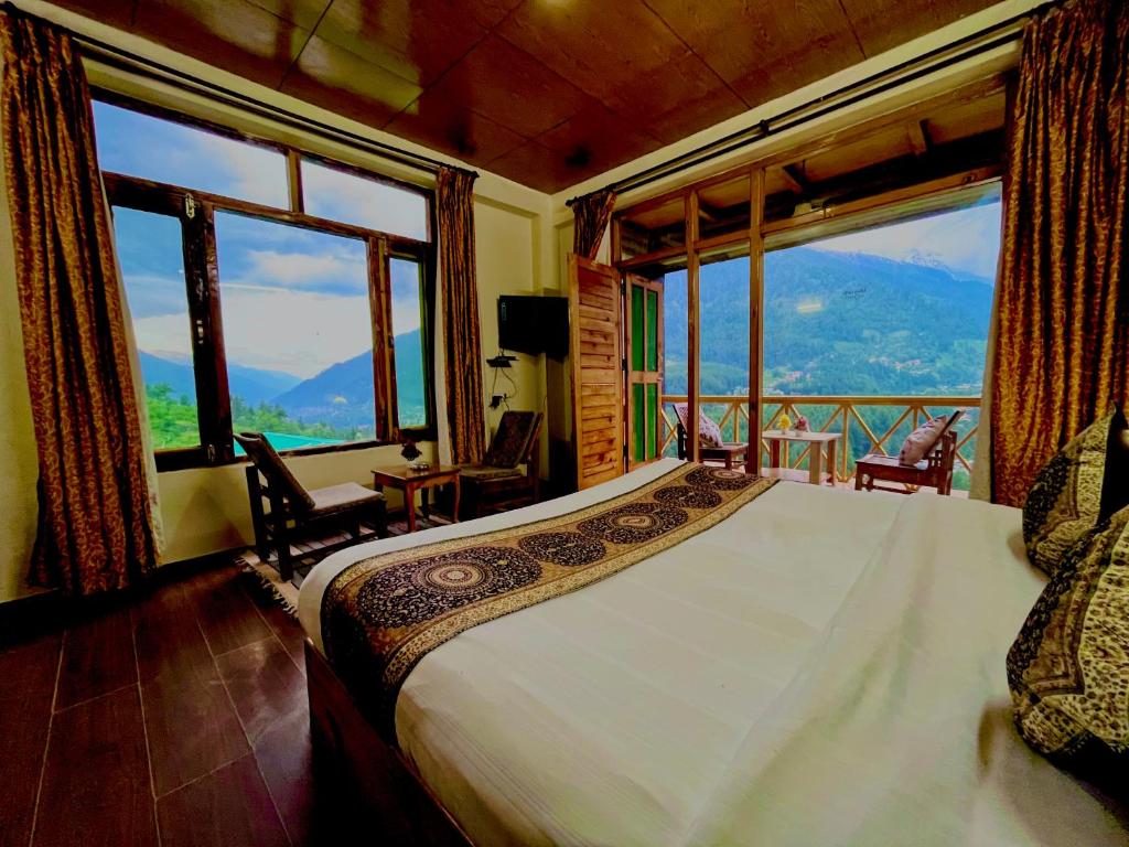 a bedroom with a bed and large windows at Bentenwood Resort - A Beutiful Scenic Mountain & River View in Manāli