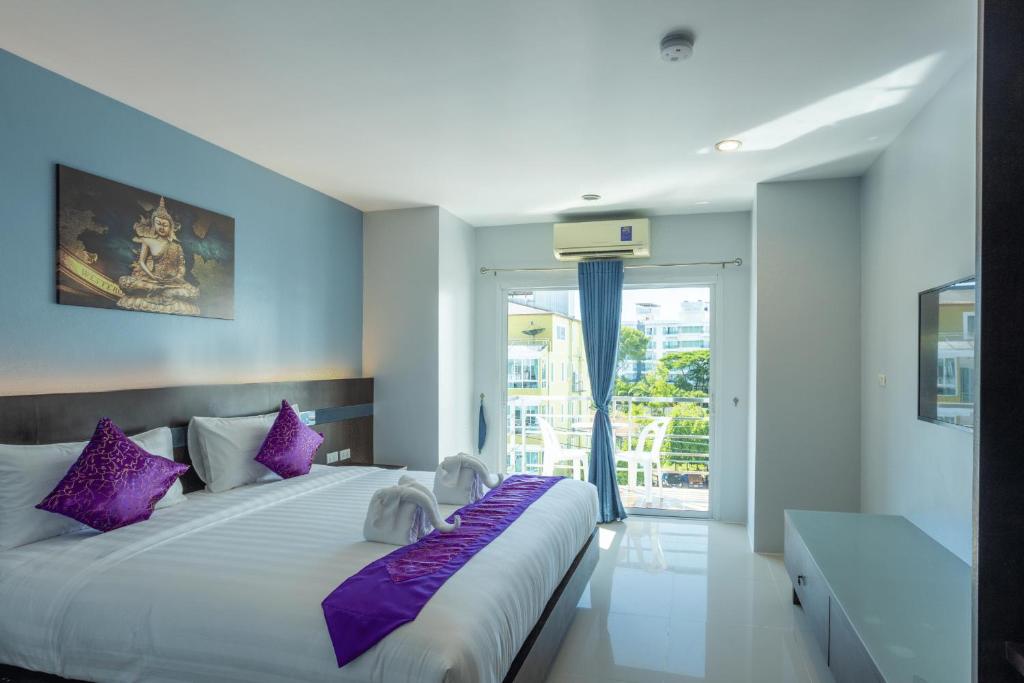 a bedroom with a large bed with purple pillows at The Great @Patong Hotel in Patong Beach
