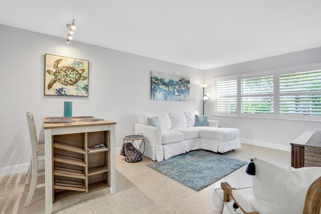 een woonkamer met een witte bank en een tafel bij Islander's Outpost in Dunedin