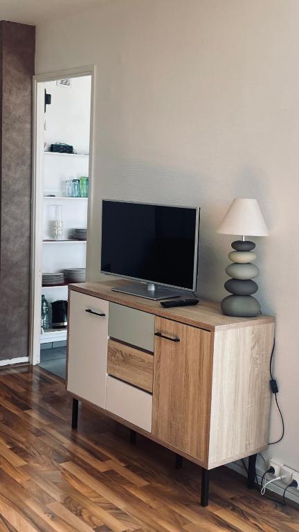 une télévision sur une armoire avec une lampe sur elle dans l'établissement LES ESSARTS T2, à Bron