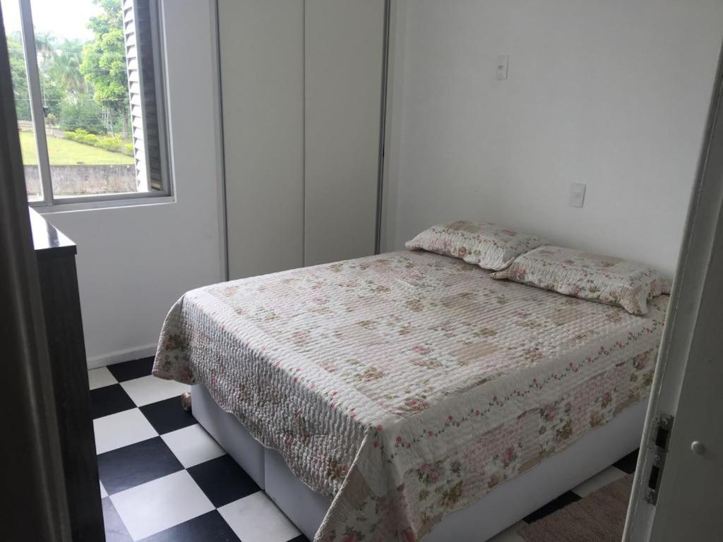 a bedroom with a bed and a checkered floor at Apartamento Compartilhado Quarto 3 Oktoberfest in Blumenau