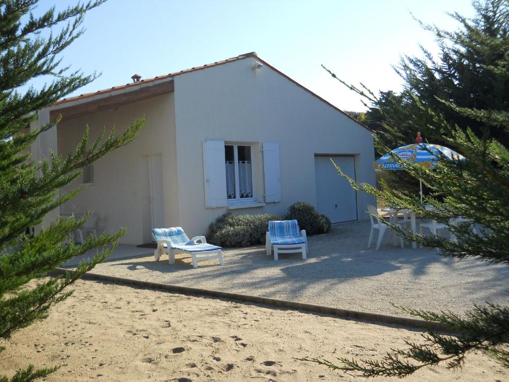 a white building with two blue chairs and a patio at Ile Oléron Près du port de La Cotinière 2 pers. Plage et océan à 50 m in Saint-Pierre-dʼOléron