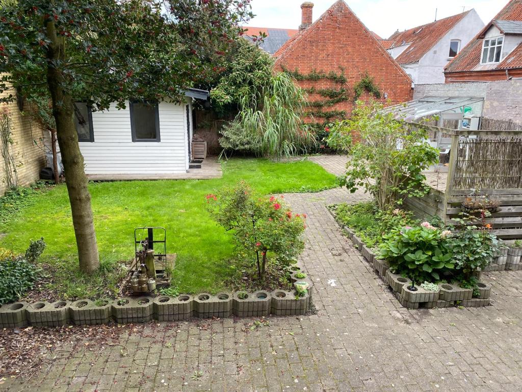 un jardin avec des fleurs et des plantes dans une cour dans l'établissement Oasen Ved Centrum, à Frederikshavn