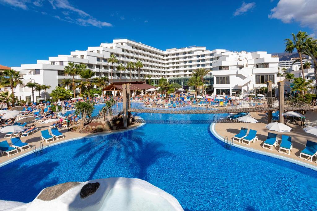 uma piscina de resort com cadeiras e um hotel em Hotel Best Tenerife em Playa de las Americas