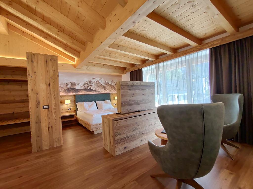 a bedroom with a bed and a desk and a chair at DOLOMITES B&B - Suites, Apartments and SPA in Tesero