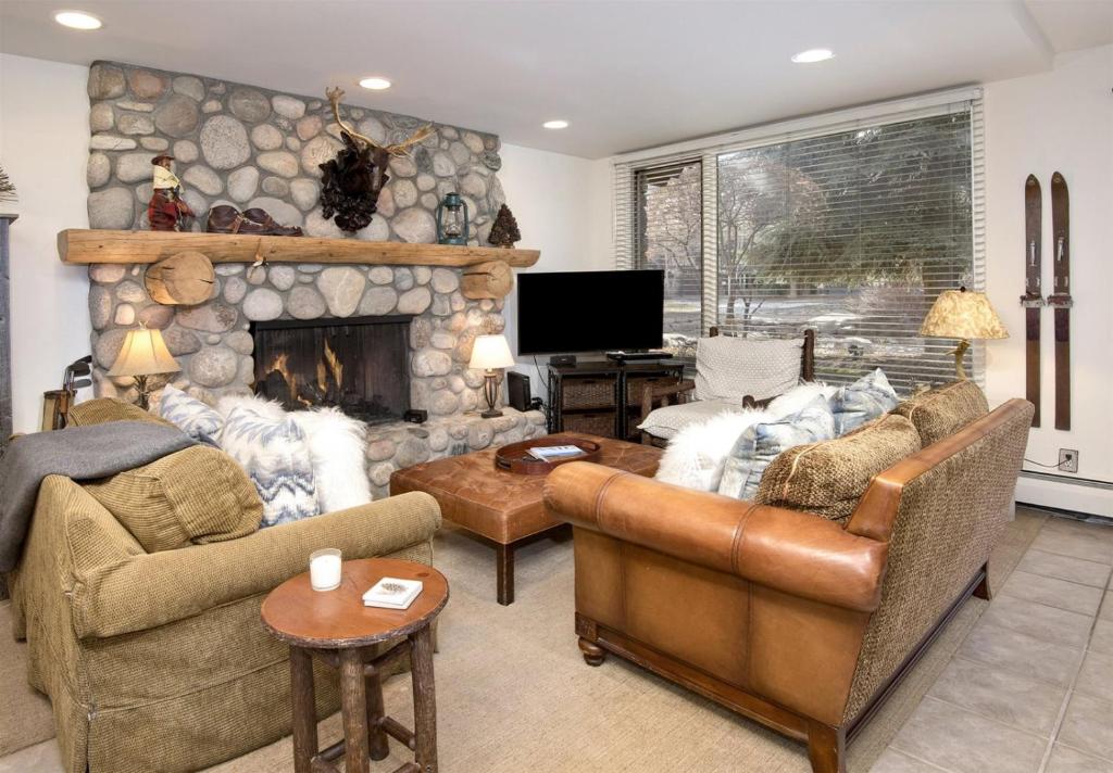 a living room with two couches and a stone fireplace at Village Center 1-e in Vail