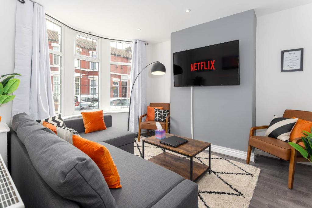 uma sala de estar com um sofá e uma televisão em Flatzy - 12 Person Townhouse with Pool Table and Ping Pong em Liverpool