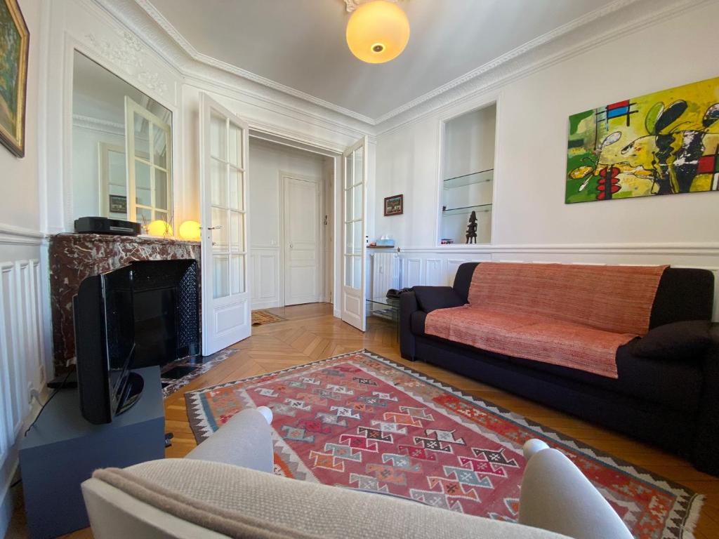 uma sala de estar com um sofá e uma televisão em Nice Sunny Central Paris em Paris