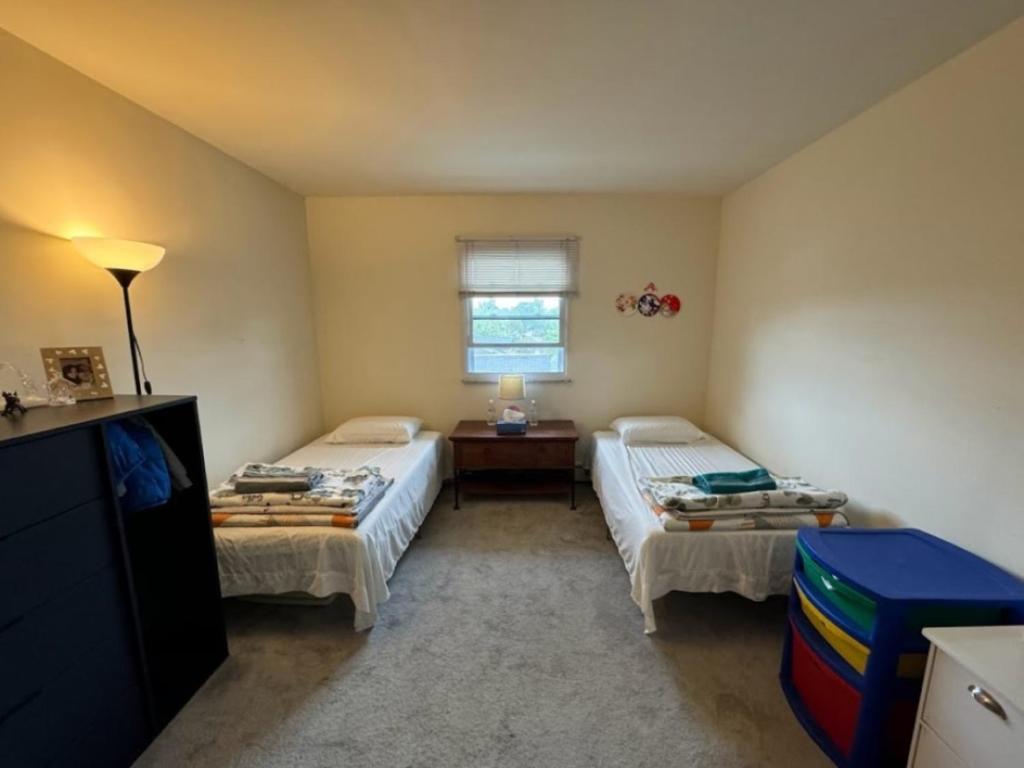 a bedroom with two beds and a table and a window at Cozy Room in Fort Lee in Fort Lee