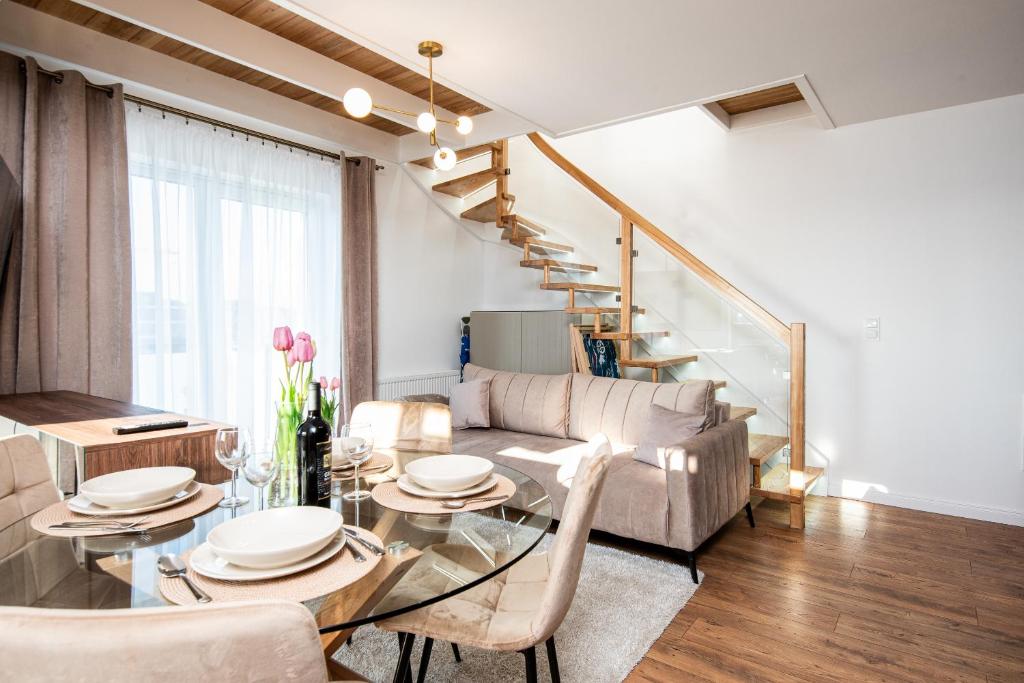 salon ze stołem i krzesłami oraz schodami w obiekcie Apartamenty PREMIUM Bałtyckie Sarbinowo 13 w Sarbinowie