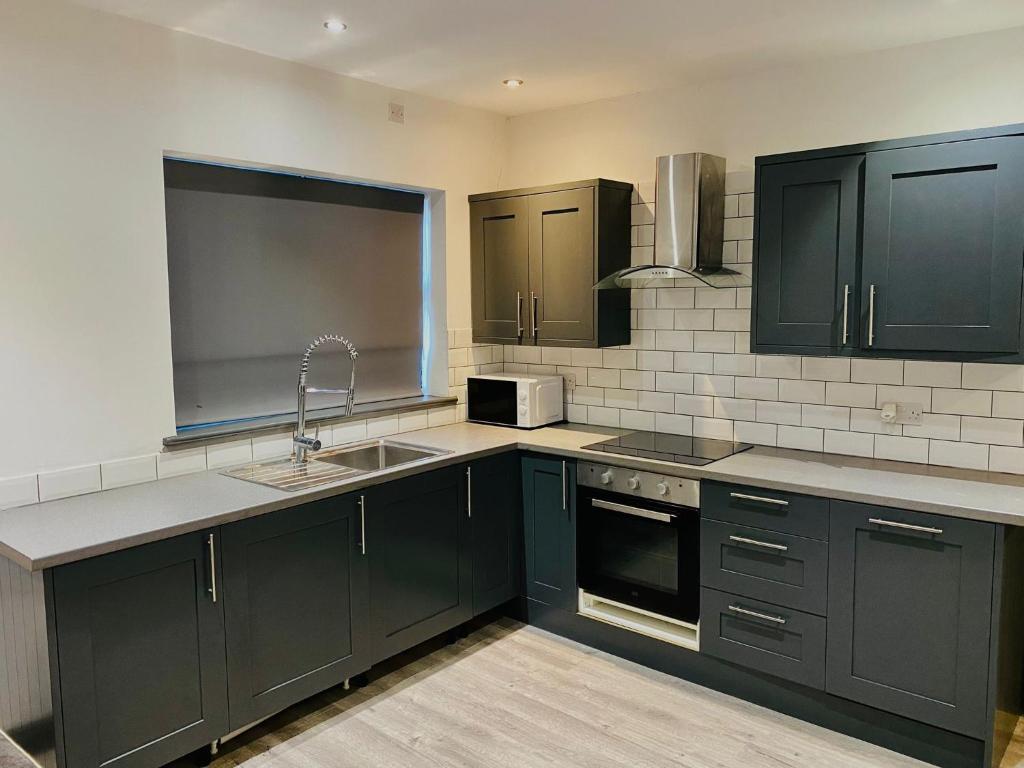 uma cozinha com armários verdes escuros e um lavatório em ABRIDGE PANORAMIC House em Theydon Bois