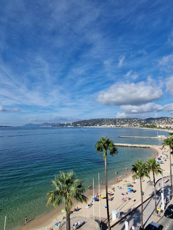 a view of a beach with palm trees and the ocean at Soleil 2023 in Antibes