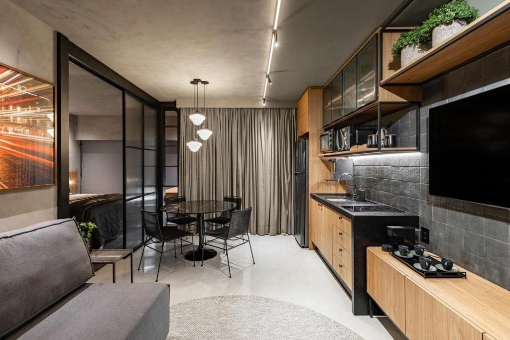 a kitchen and dining room with a table and a television at Studio London in Campo Grande