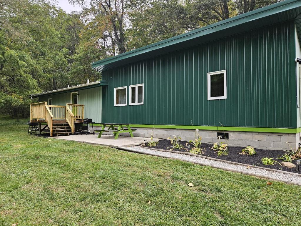 a green building with a picnic table in front of it at Frog Hollow at Hocking Vacations in Logan