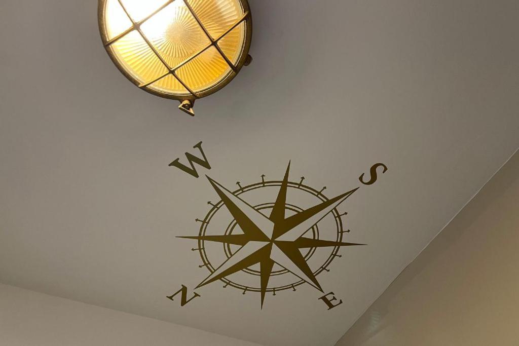 a compass clock on a wall with a light at Whitstable The Jolly in Whitstable