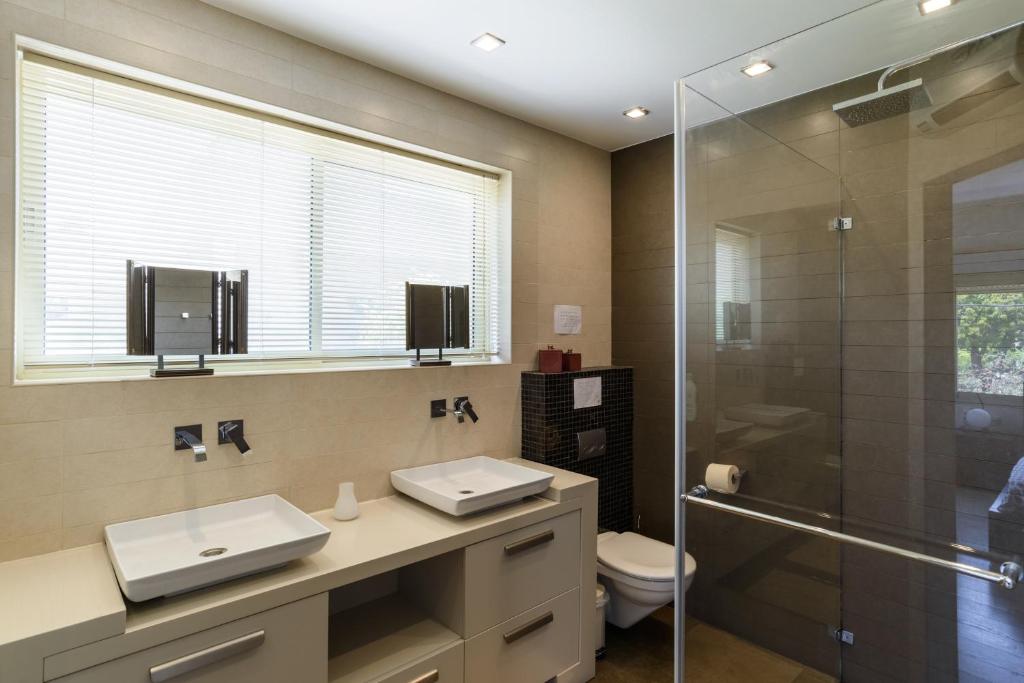 La salle de bains est pourvue de 2 lavabos et d'une douche en verre. dans l'établissement Maison d architecte, à Herzliya