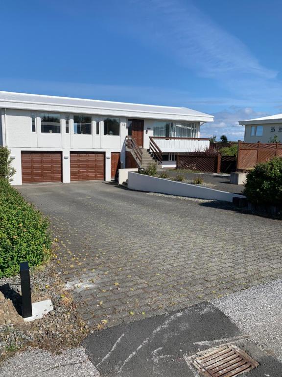 a white house with a driveway in front of it at Mengi Apartments Keflavik in Keflavík