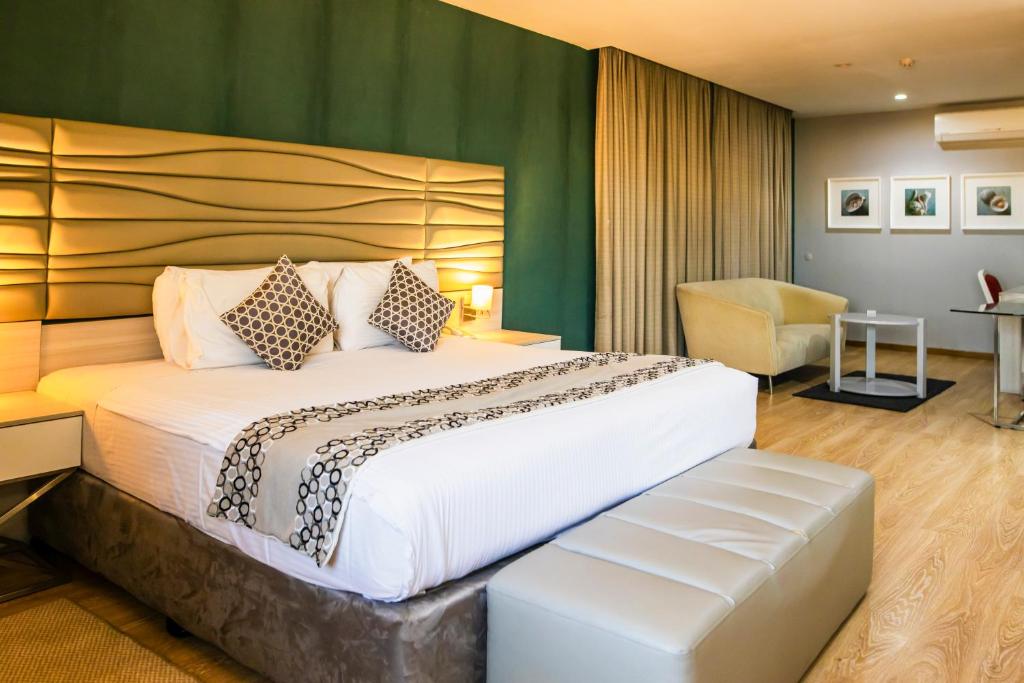 una habitación de hotel con una cama grande y una silla en WL Hotel Maputo City Center Mozambique Collection, en Maputo