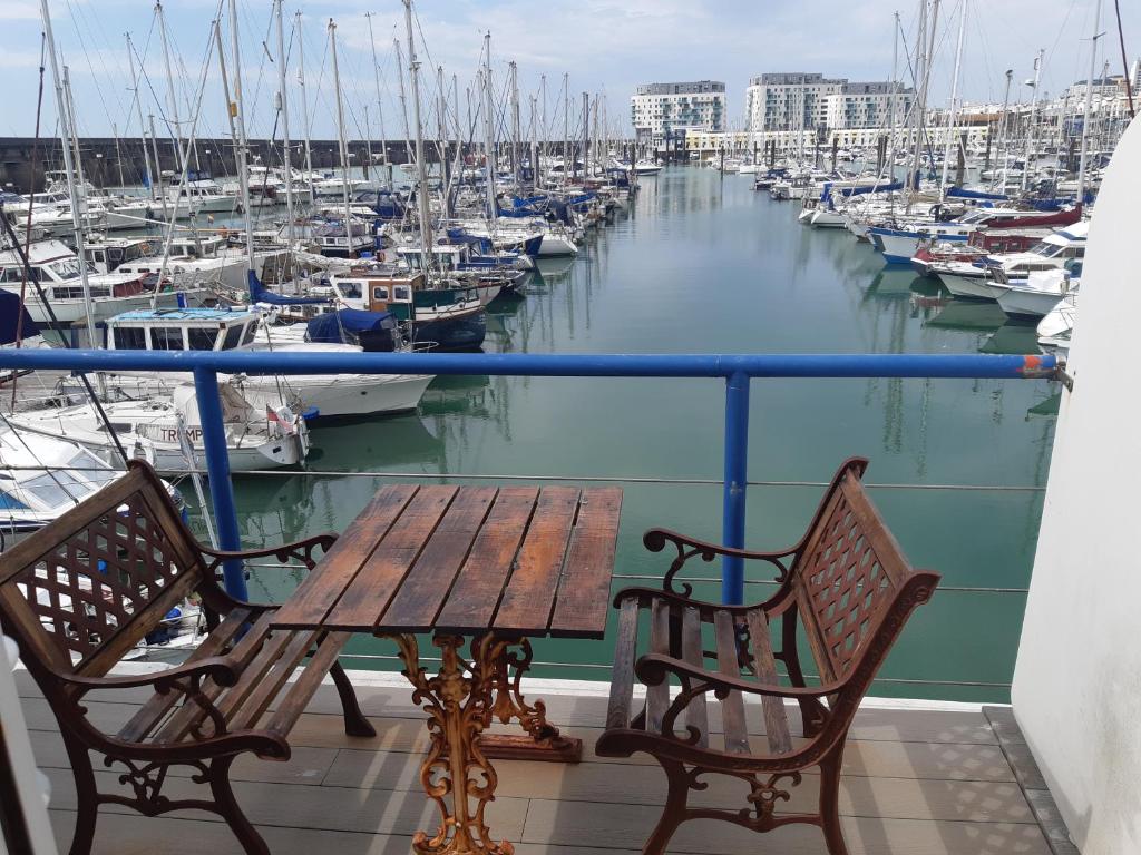 een tafel en 2 stoelen op een balkon met uitzicht op een jachthaven bij Fantastic Waterside apartment in Brighton Marina in Brighton & Hove
