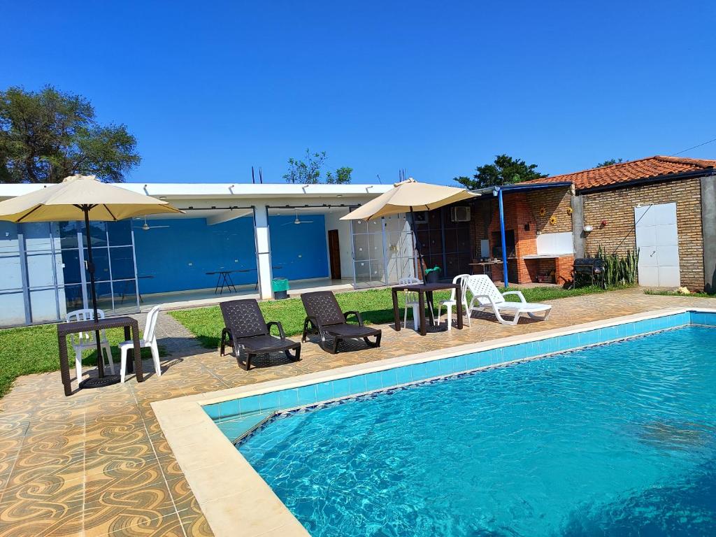 a swimming pool with chairs and umbrellas next to a house at ALOJAMIENTO ASPEN HOME in San Lorenzo de la Frontera