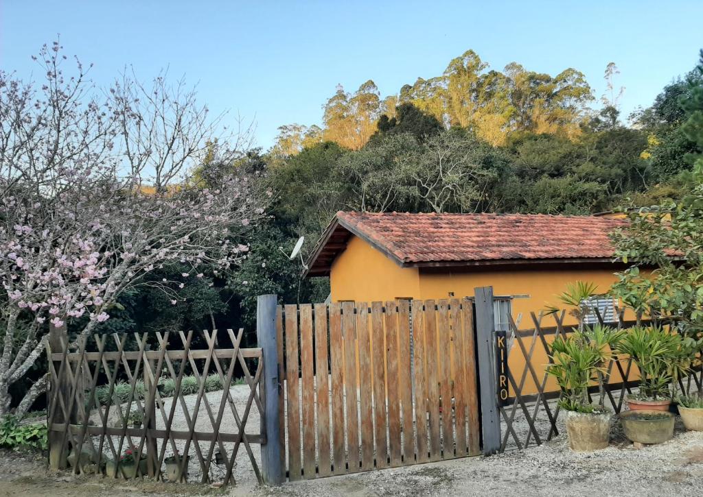 uma casa amarela com um portão de madeira em frente em Casa Kiiro, um ambiente tranquilo e de sossego. em Santo Antônio do Pinhal