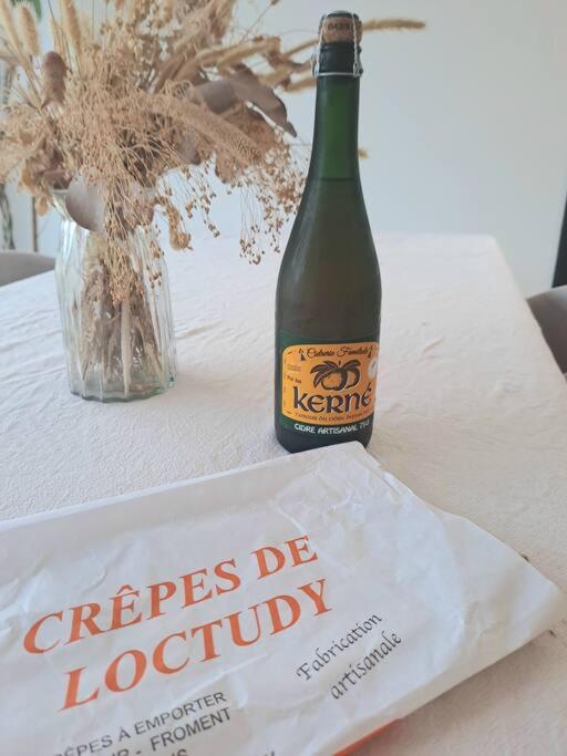 a bottle of wine sitting on a table with a book at Maison de vacances à Loctudy in Loctudy