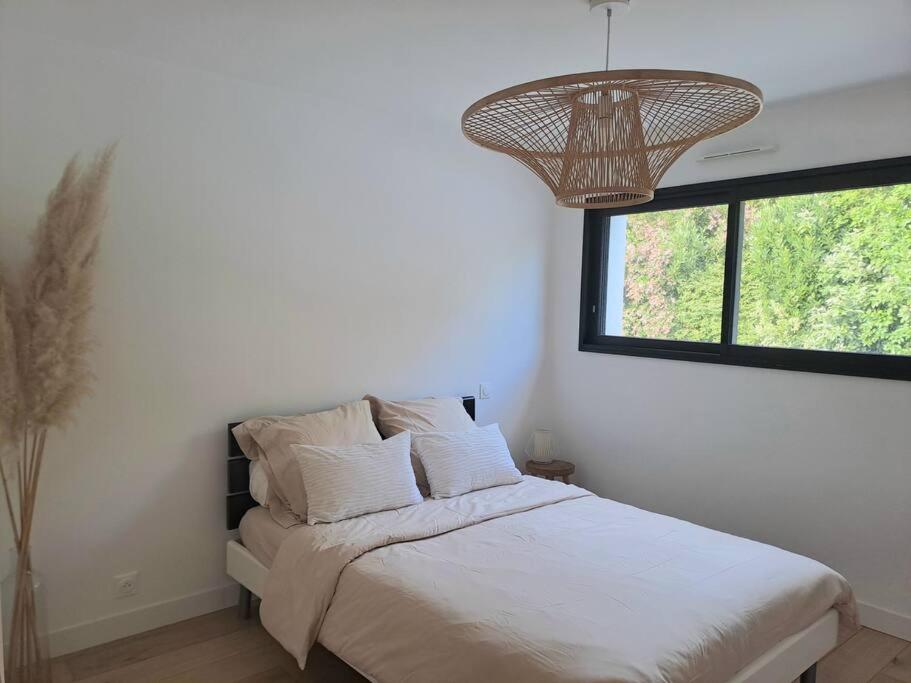a bedroom with a bed with a chandelier and a window at Maison de vacances à Loctudy in Loctudy