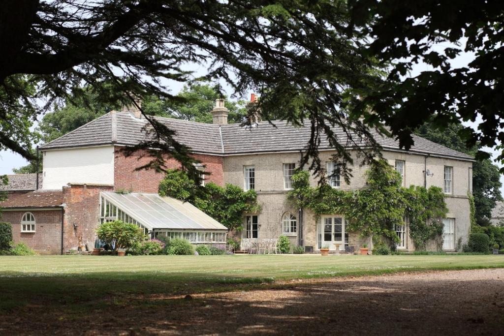 a large brick house with a green lawn in front of it at Highfield Farm in Fakenham