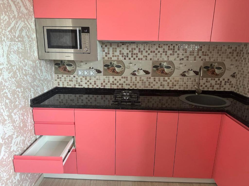 a kitchen with pink cabinets and a microwave at Днестровский in Kharkiv