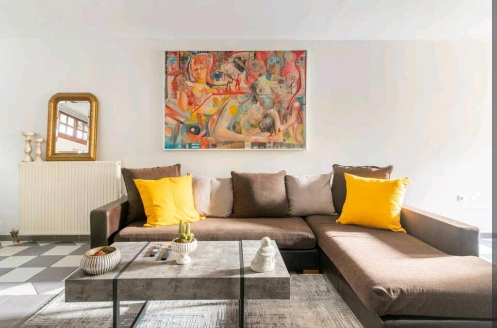 sala de estar con sofá marrón y almohadas amarillas en Stunning studio near center of athens en Atenas
