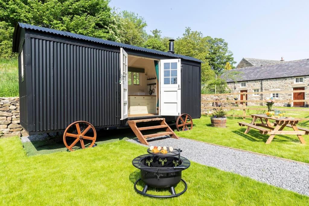 a black tiny house with a grill in the yard at Dilly Hill Den in Stanhope