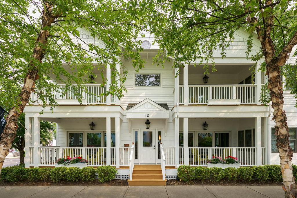 una casa bianca con una veranda bianca e alberi di The Neighborhood Hotel New Buffalo a New Buffalo