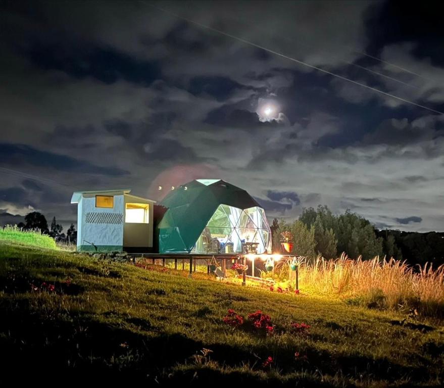 een koepelhuis op een veld 's nachts bij glamping casa blanca in Guatavita