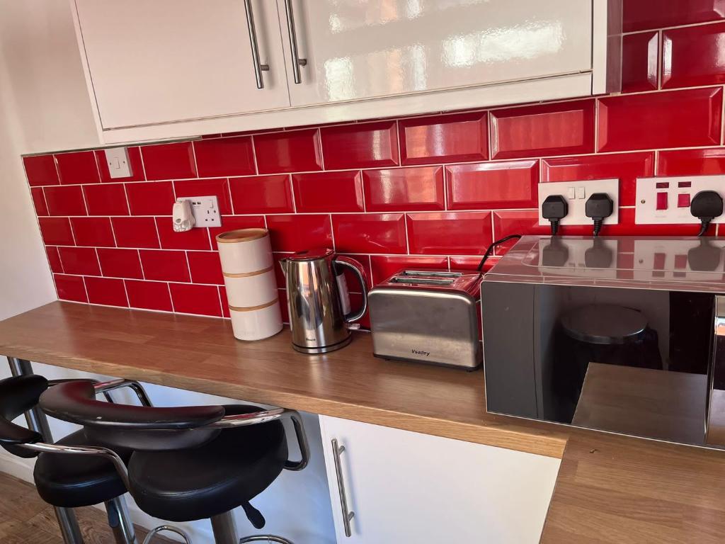 a kitchen with a counter with a microwave and red tiles at Inviting Town House in Coventry
