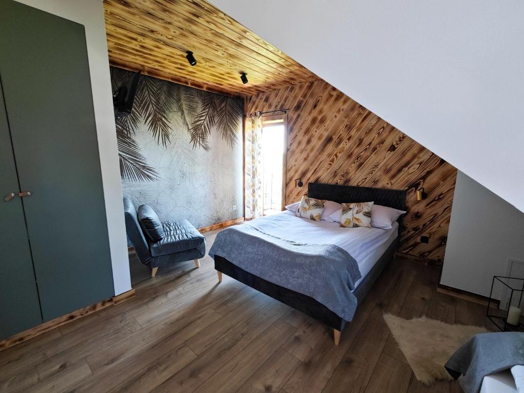een slaapkamer met een bed en een houten muur bij Pokoje Gościnne i Apartament Górski Widok in Czarna Góra