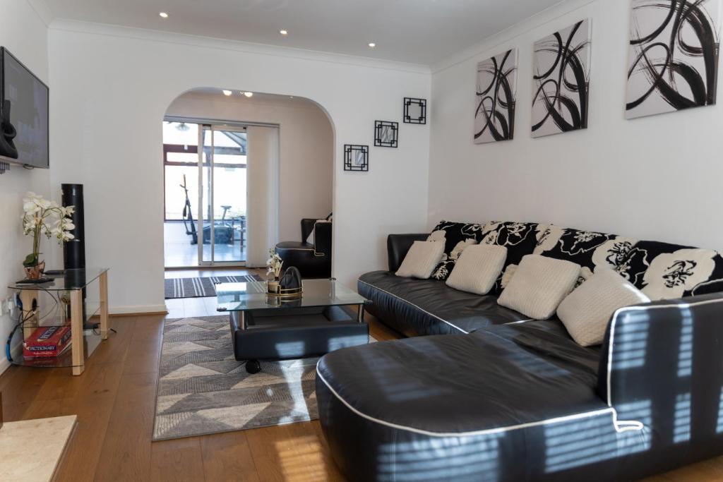 a living room with a black couch and a table at 4 bedroom home - free parking by Ideel Apartments in Milton Keynes in Wolverton