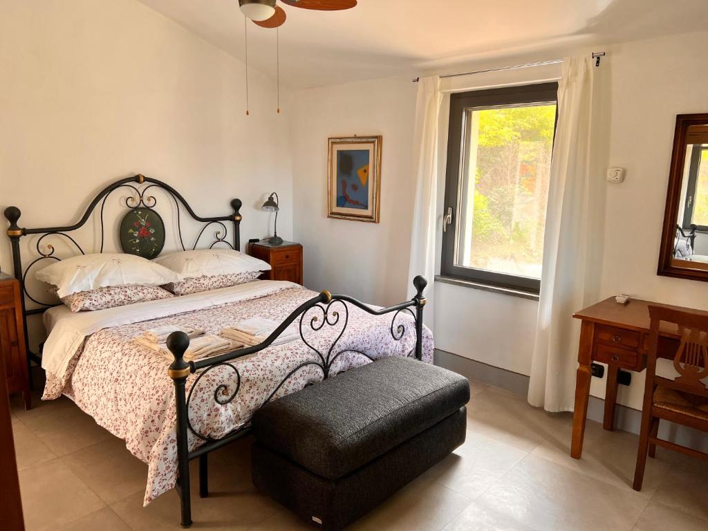 a bedroom with a bed and a chair and a window at La Fontanella Country House in Celle sul Rigo