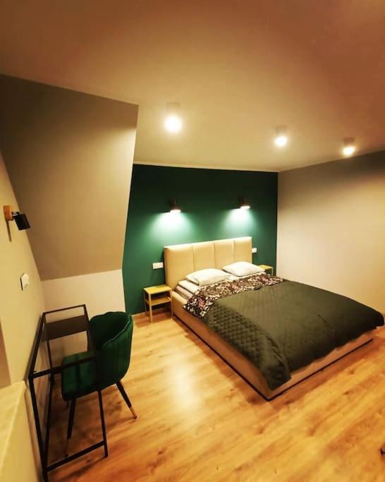 a bedroom with a bed and a green wall at Apartament Nadwodnia 37 in Łapsze Niżne