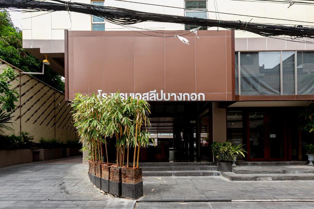 um edifício com uma árvore em frente em A Sleep Bangkok Sathorn em Banguecoque