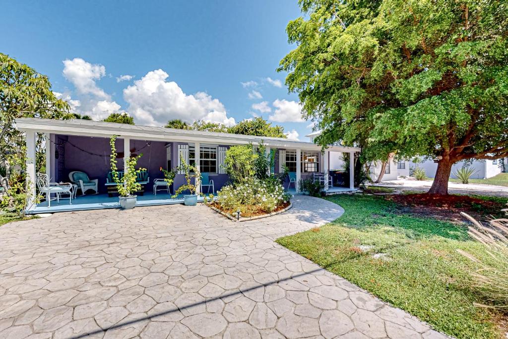 a house with a patio and a tree at Purple Pelican Cottage in Marco Island